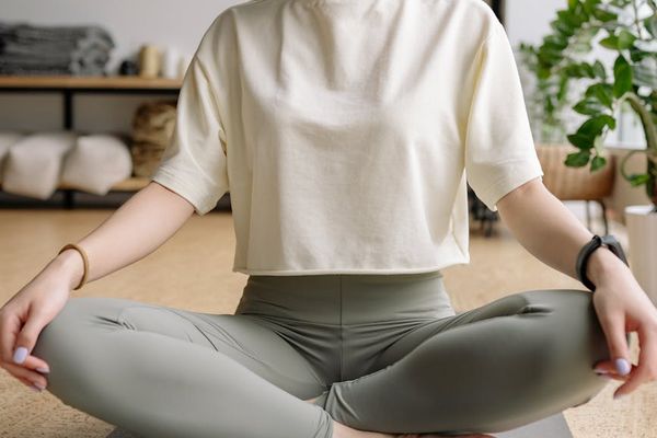A person sitting in a meditative yoga pose with eyes closed, embodying calmness.